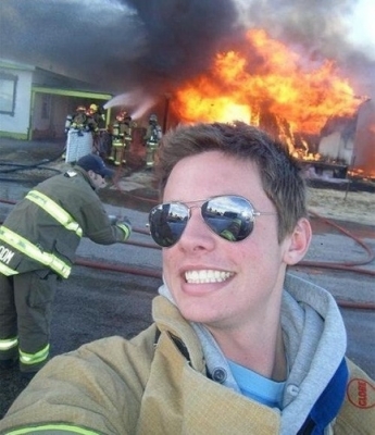 A house is engulfed by flames but this guy thinks it's the perfect opportunity to take a selfie.